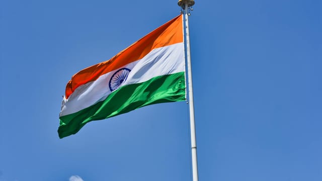 The Indian national flag waving against a clear blue sky symbolizes patriotism and national pride.