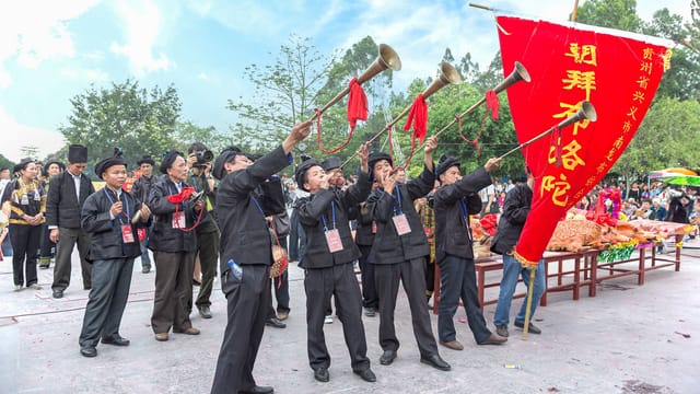 A vibrant street parade with musicians and banners during a traditional festival in Guangxi, China.