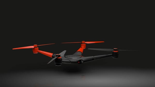 Red and black drone captured mid-flight against a sleek dark background.