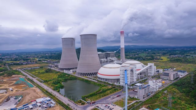 Aerial shot of a nuclear power plant in Jiangxi, China, with cooling towers and surrounding landscape.