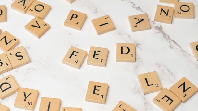 Scrabble tiles arranged to spell 'FED' on a marble surface, symbolizing finance.