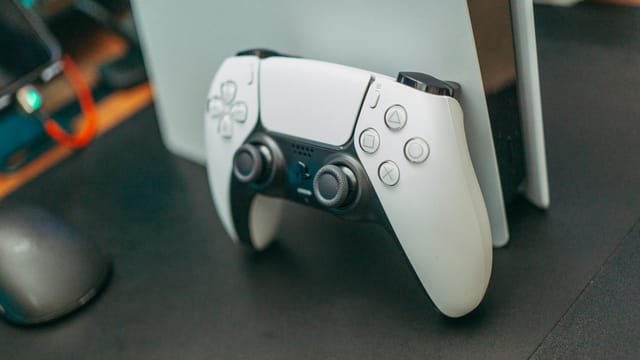 Close-up of a PlayStation 5 controller resting on its console, showcasing modern gaming technology.