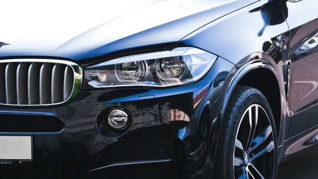 Close-up of a black luxury car showcasing intricate headlight and front grille details.