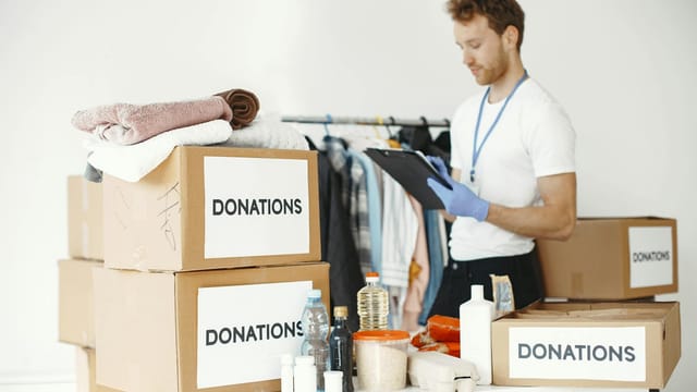 Volunteer organizing various goods for donation. Charitable cause and community support.