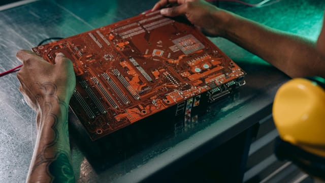 Close-up of a technician working on a circuit board in an industrial setting.