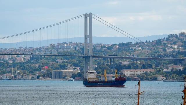 A ship navigates through the Bosphorus Strait under the iconic Bosphorus Bridge in Istanbul, Türkiye.