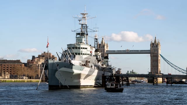 View of HMS Belfast moored on the River Thames with Tower Bridge in the background in London.