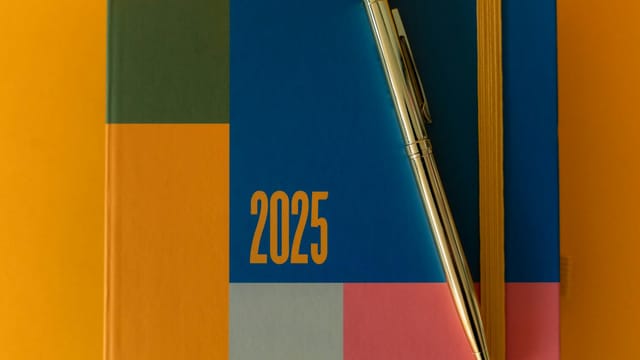 A vibrant 2025 planner with a pen on a colorful backdrop, ideal for organization.