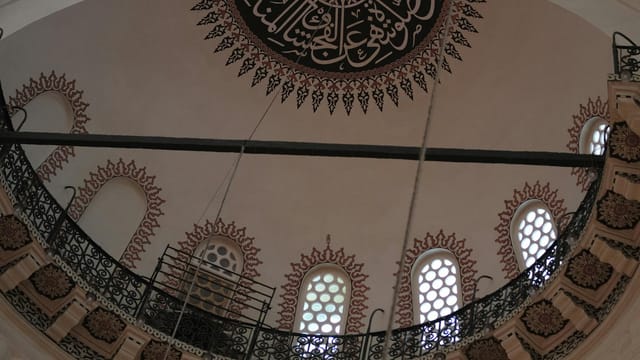 Detailed view of a mosque dome showcasing traditional Islamic calligraphy and architecture.