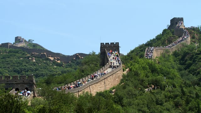A breathtaking view of the Great Wall of China with lush greenery and historic architecture.