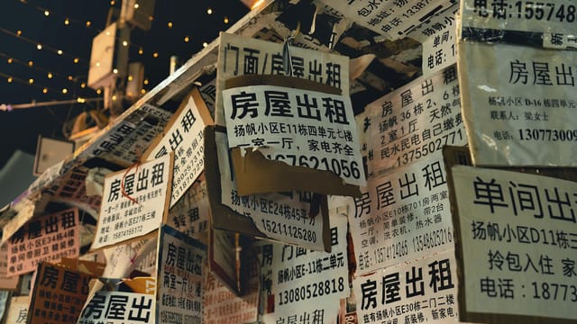 Close-up of numerous Chinese real estate posters displayed at night with warm lighting.