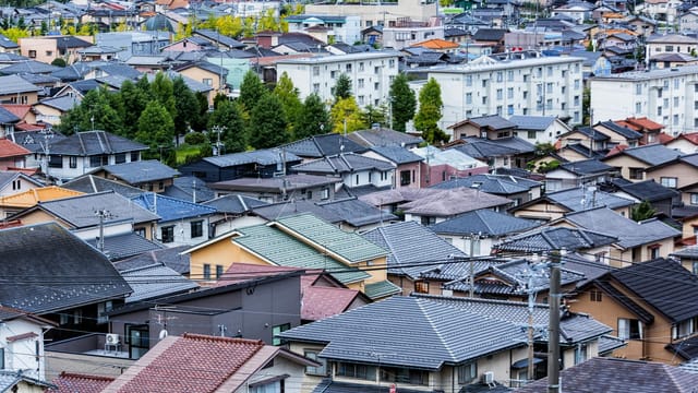 Aerial view of traditional Japanese roofs in an urban neighborhood at daytime.