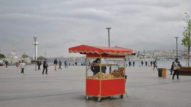 Street vendor selling simit by the Bosphorus in Istanbul on a cloudy day.