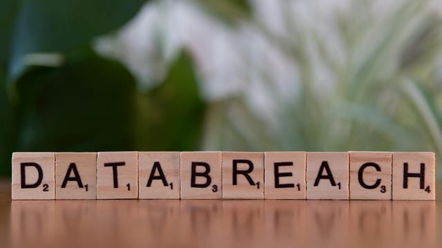 Close-up of Scrabble tiles spelling 'data breach' on a blurred background