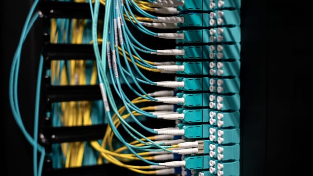 Closeup of switch in server with connectors and adapters connected to plastic device in dark room on blurred background inside