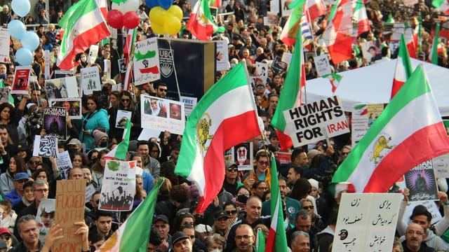 A peaceful protest in Vancouver advocating for human rights in Iran, featuring vibrant flags and diverse participants.