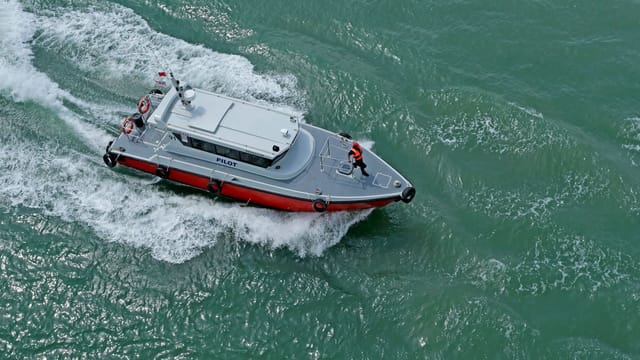 Dynamic aerial shot of a pilot boat cutting through the sea waves.