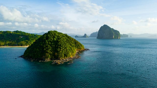 A breathtaking aerial view of the lush green islands of El Nido, Philippines, surrounded by crystal blue waters.