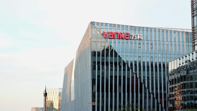 Contemporary glass office building with Vanke signage in urban area.