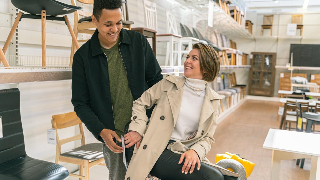 A couple happily explores a furniture store filled with stylish chairs and decor, showcasing modern lifestyle.
