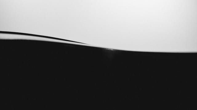 Minimalist abstract black and white image showcasing smooth wave-like forms.