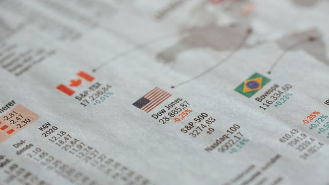 Detailed close-up of a newspaper displaying global financial market statistics and country flags.