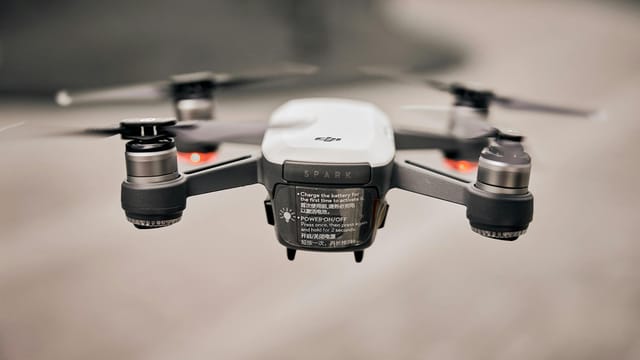 Close-up of a modern drone flying outdoors, showcasing advanced technology and propellers.