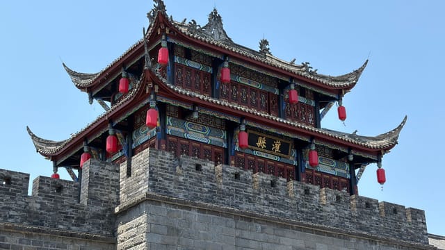 A stunning traditional pagoda with red lanterns in Sichuan, China, under a clear blue sky.