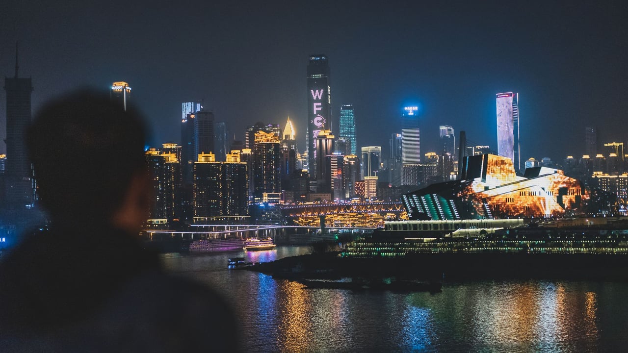 Back view unrecognizable blurred male enjoying amazing view of contemporary illuminated embankment in Chungking China during night