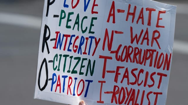 A protest sign emphasizing pro-love, peace, and integrity, against hate and war.