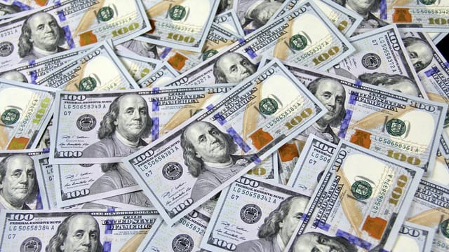 Pile of US hundred dollar bills depicting financial success and wealth.