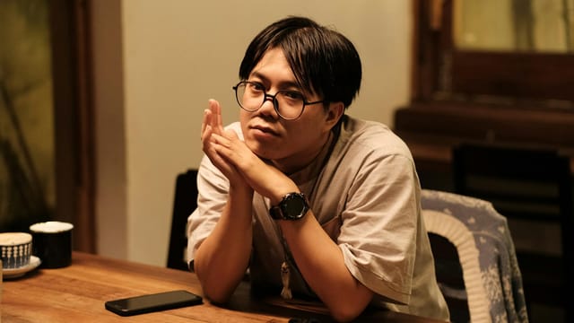 Thoughtful portrait of a person sitting indoors in a Vietnamese cafe. Capturing mood and style.