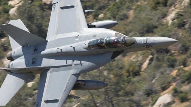 F-18 Super Hornet flying over rocky terrain in Kernville, California. Dynamic and powerful military aircraft.
