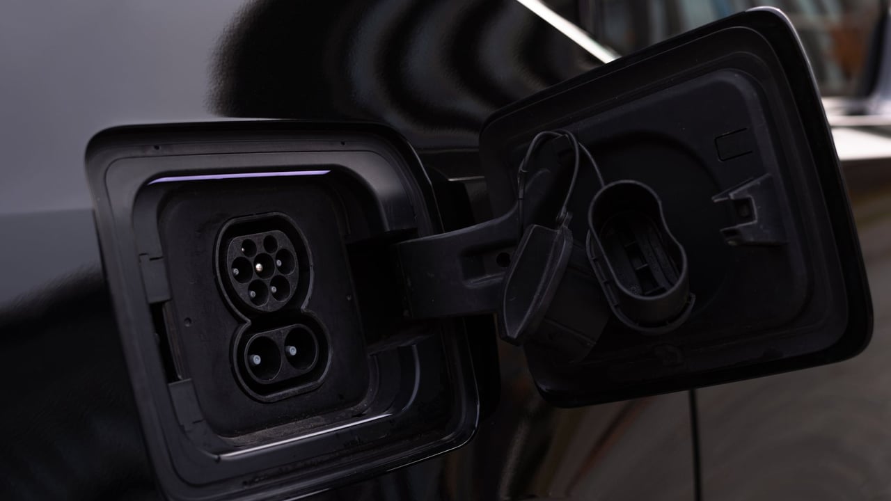Illustrative image: Close-up image of an electric vehicle charging port on a black car.
