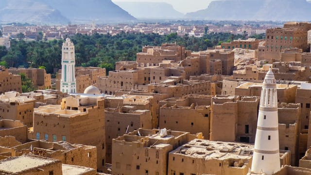 Aerial view showcasing the traditional architecture of a historic town in Yemen with iconic towers and desert landscape.