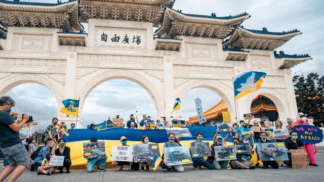 Protesters gather with Ukrainian flags at Liberty Square, advocating for peace and democracy.