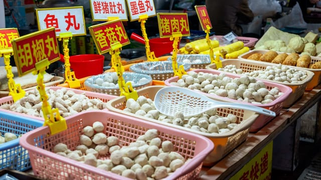 Vibrant street market stalls with various fish balls on display in Jieyang, Guangdong, China.