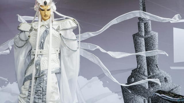 Close-up of a mystical warrior doll in white attire with a tower backdrop, evokes fantasy art.