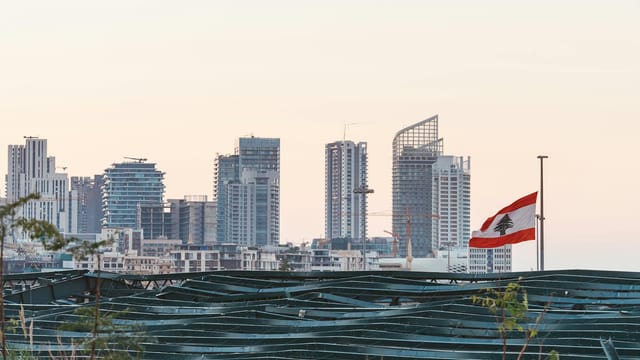 Captured view of Beirut's skyline with the Lebanese flag during sunset, showcasing urban architecture.