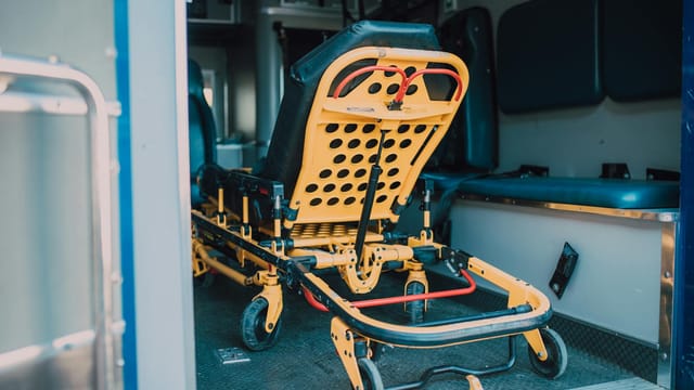 A detailed view of a yellow emergency stretcher inside an ambulance, ready for use.