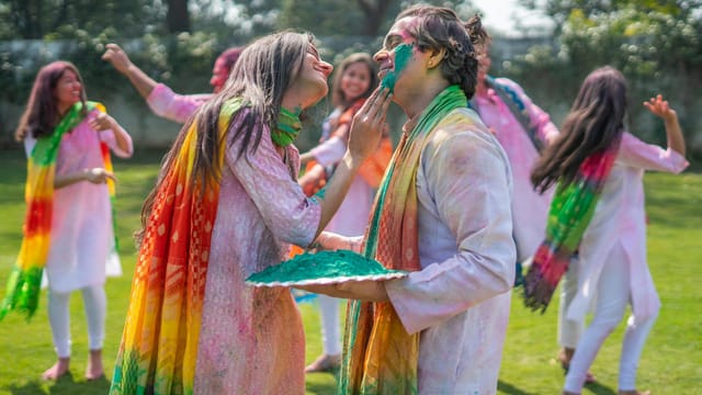 Group enjoying colorful Holi festival outdoors with laughter and joy.