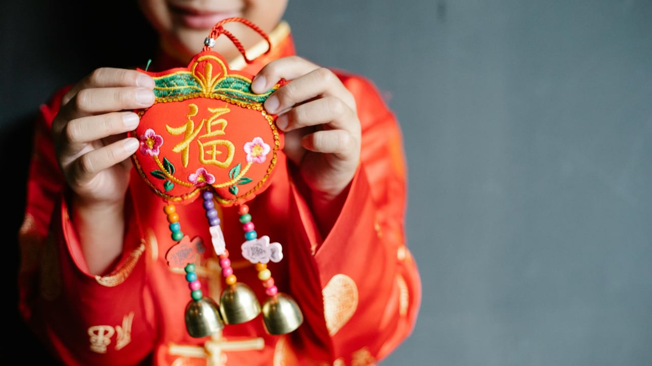 Young boy displaying colorful Chinese New Year ornament, symbolizing luck and joy.