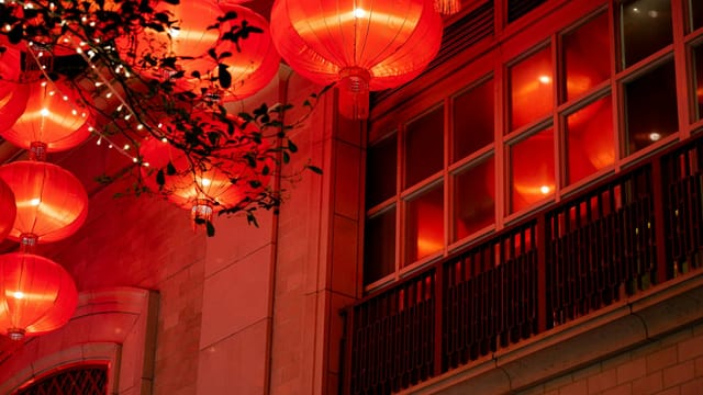 Illuminated red Chinese lanterns hanging at night in Hong Kong, adding cultural elegance to the urban setting.