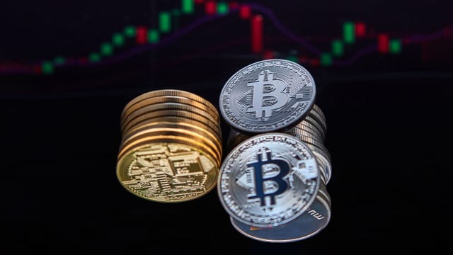 Closeup of Bitcoin coins with a market chart in the background showing financial trends.