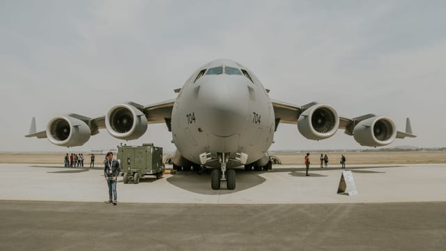 Front view of C-17 Globemaster with crew standing around on a sunny day at an airport.