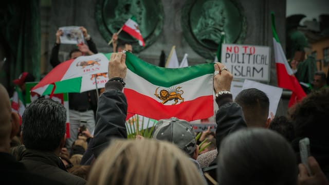 Protest in Stockholm with Iranian flags and social issue slogans.