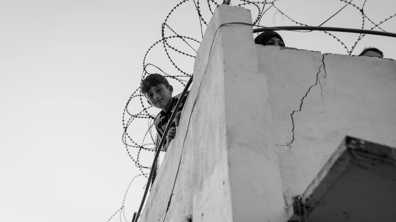 A child looks over a barbed-wire balcony, symbolizing hardship in Lebanon.