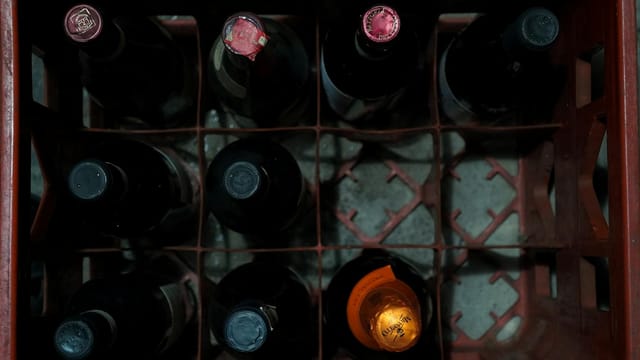 Overhead shot of assorted wine bottles in a red plastic crate showcasing storage arrangement.