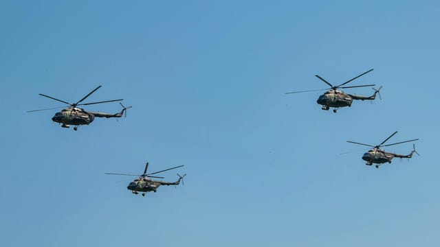 Four military helicopters flying in formation against a clear blue sky in Belgrade, Serbia.