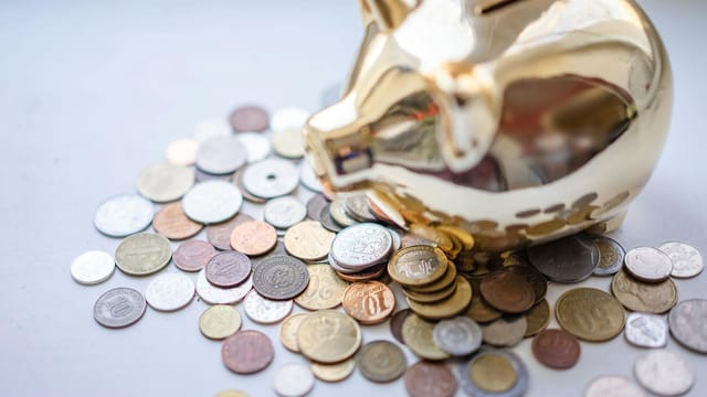A golden piggy bank surrounded by assorted coins, symbolizing savings and wealth.